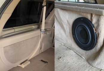 The inside of the back of a car on one side of the image, a speaker installed into upholstery on the other